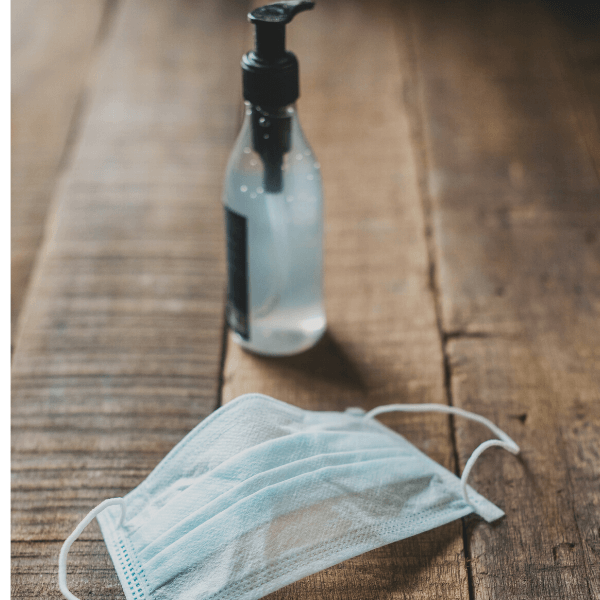 A protective face mask next to a bottle of hand sanitizer.