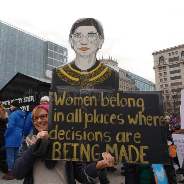 A woman standing at the Women's March and holding a sign with a drawing of Justice Ruth Bader Ginsburg.