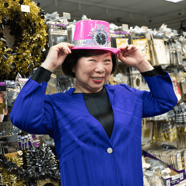Wendy Shen standing in a store holding a pink hat on top of her head.