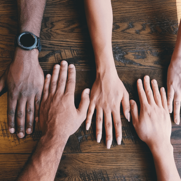 Five hands next to each other on a table.