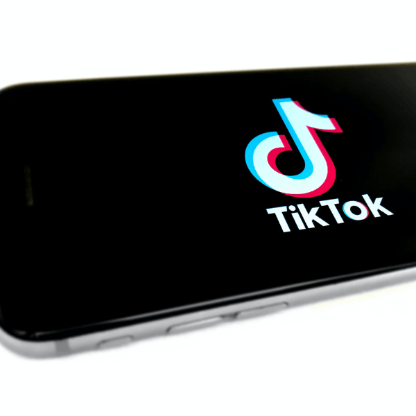 The logo of TikTok is displayed on an iPhone against a black screen.