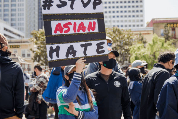 A person at a protest holding a sign that reads "Stop Asian Hate"