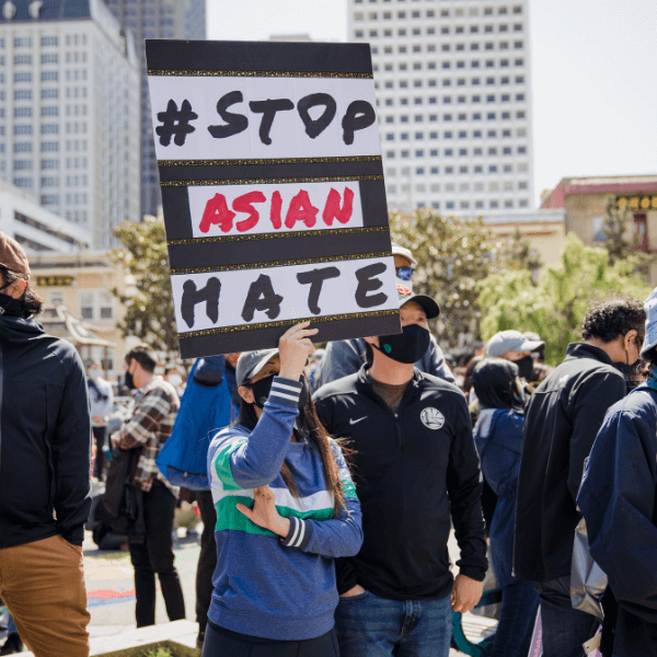 A person at a protest holding a sign that reads "Stop Asian Hate"