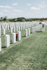 A soldier kneels at graves in a veteran cemetary
