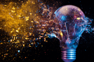A photo of a lightbulb against a black background. Gold dust and multi-colored glitter is exploding from the light bulb.