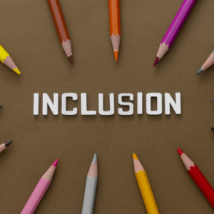 The word "inclusion" is written in white lettering against a brown background. 10 colored pencils of various colors and framing the word along the edge of the photo. 
