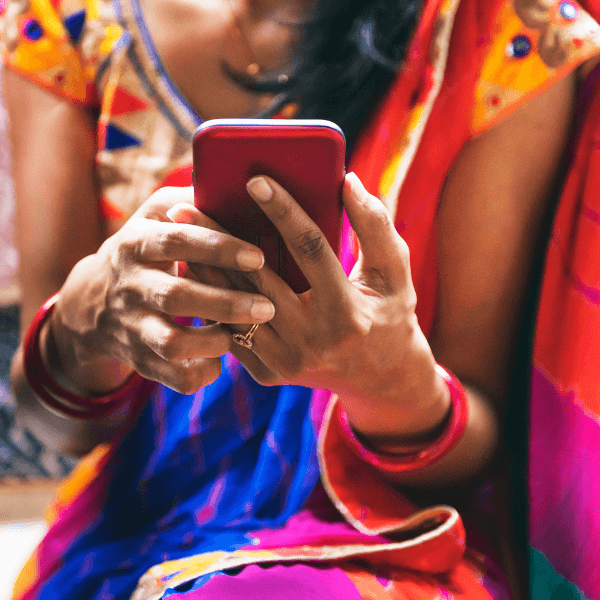 A photo of a woman holding a smartphone in both of her hands as she types on it.