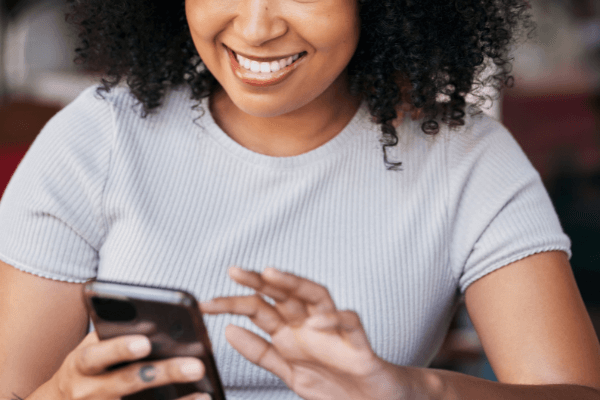 A woman is sitting in a chair as she is scrolling on her phone and reading what is on the screen.