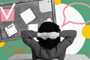 A black and white photo of a woman sitting at a desk with her hands around her head against a green background with a bulletin board depicting illustrations of planning a business.