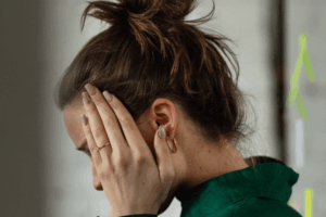 The side profile of a woman holding her head in her hands.