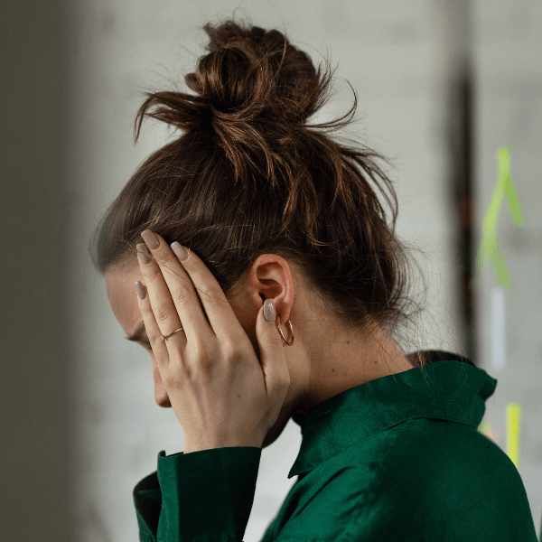 The side profile of a woman holding her head in her hands.