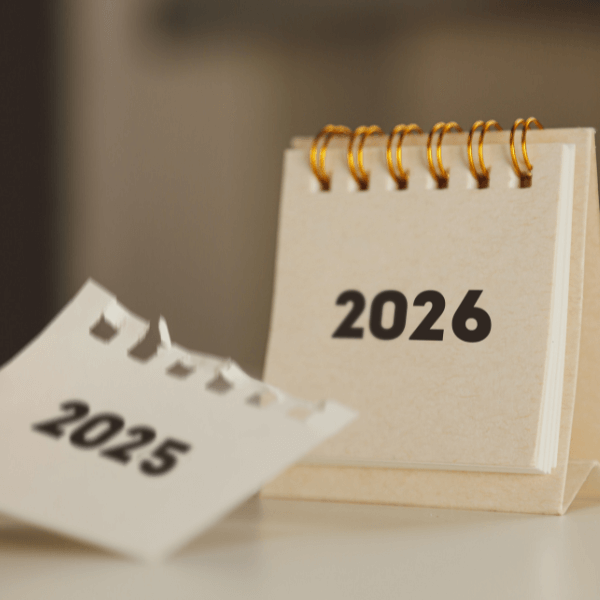 A desk calendar notepad that has "2026" in black text with a torn paper falling to the desk that has "2025" in the same black font written on it.