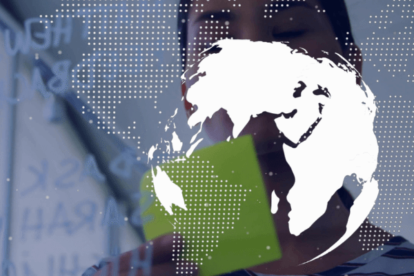 A POV from behind a screen of a woman looking at an outline of a map of the Earth.