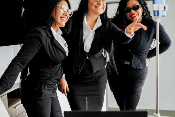 Three Latina entrepreneurs taking a picture using an iPhone on a tripod.